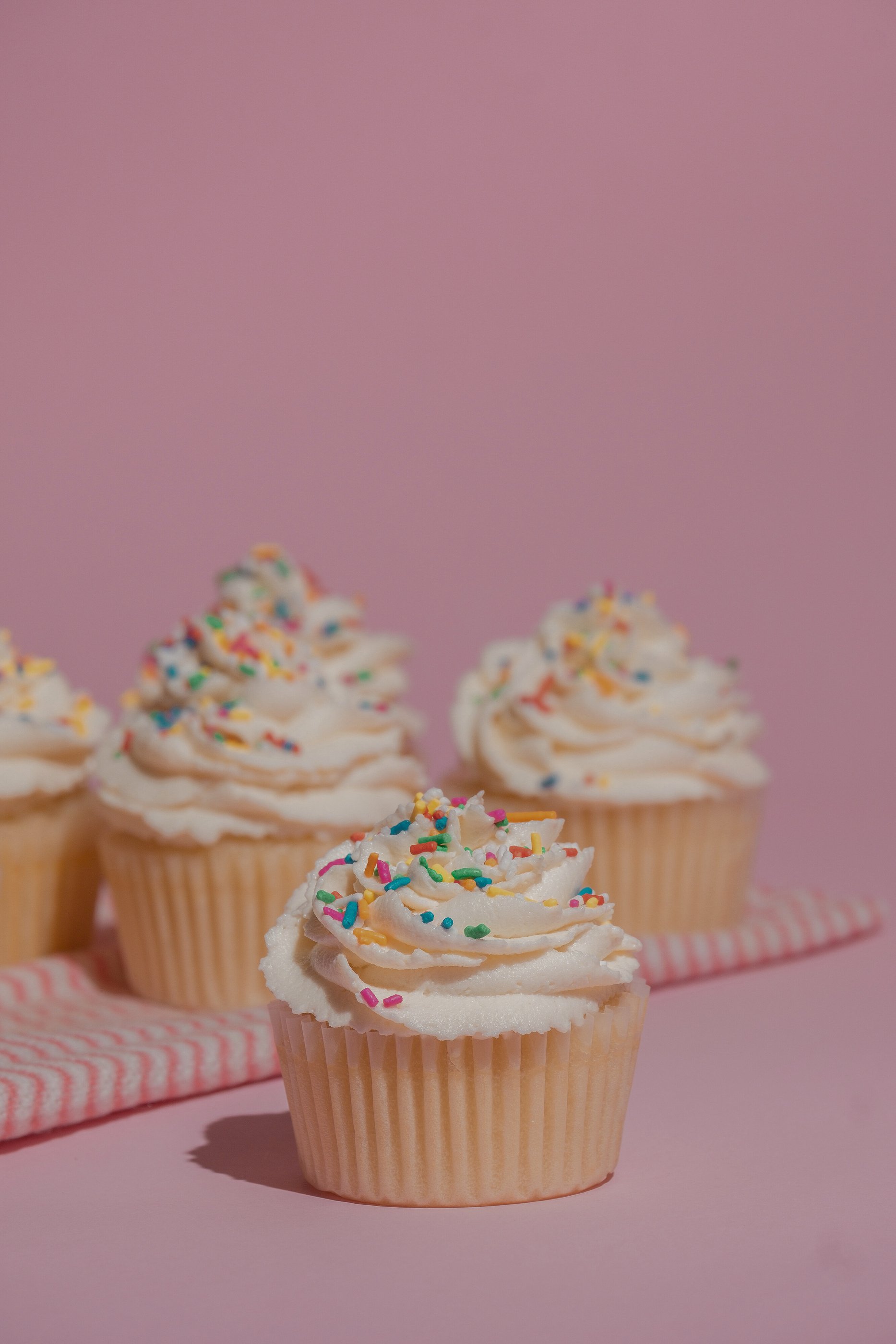 Cupcakes with Frosting and Sprinkles on Pink Background