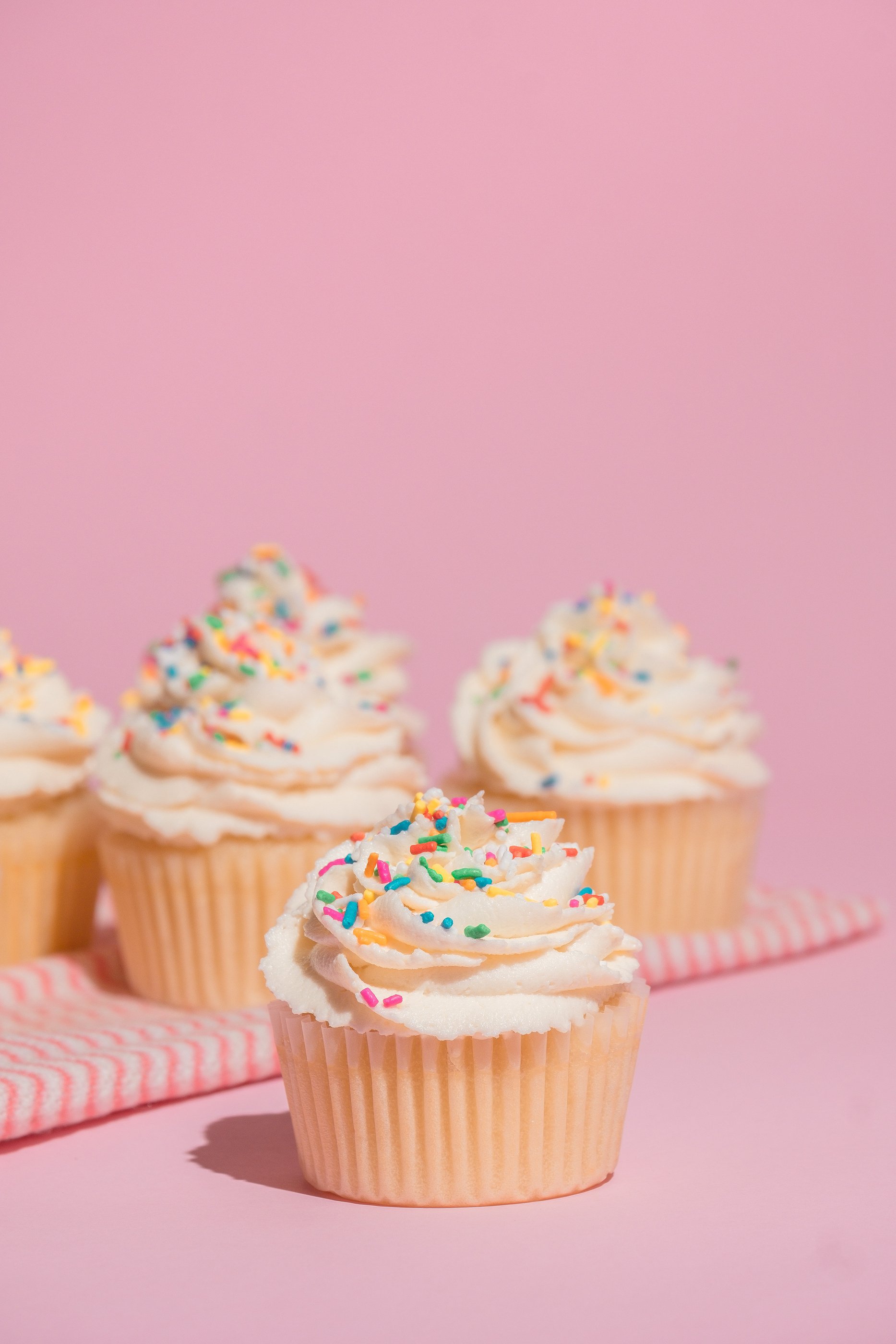 Cupcakes with Frosting and Sprinkles on Pink Background